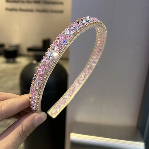 Detailed close-up of a gold headband with sparkling pink and clear crystals