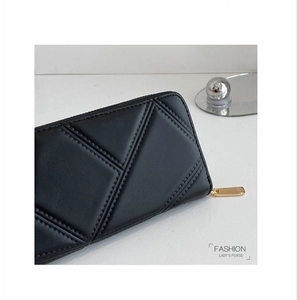 Detailed view of women's black long wallet with geometric quilted pattern and gold zipper