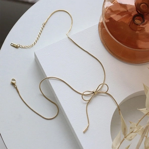 Detailed macro view of 18KGP gold bow necklace with sleek snake chain and lobster clasp