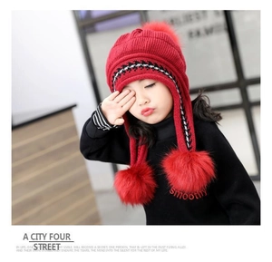 Dettaglio cappello in maglia rossa per bambini con paraorecchie e tre pompon soffici