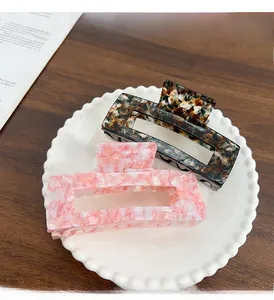Close-up of pink marble and dark tortoiseshell acetate claw clips in a porcelain dish
