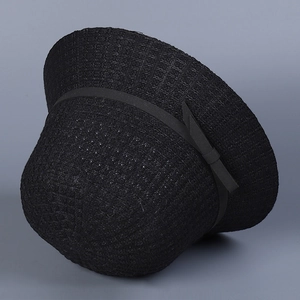 Detailed view of the woven black straw sun hat featuring a delicate grosgrain ribbon bow