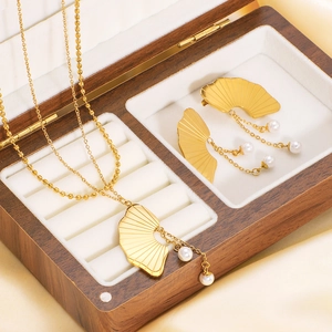 Golden fan-shaped pearl necklace and earrings set displayed in a wooden jewelry box