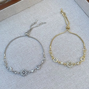 Detail of adjustable zircon flower bracelets in gold and silver plating on linen display