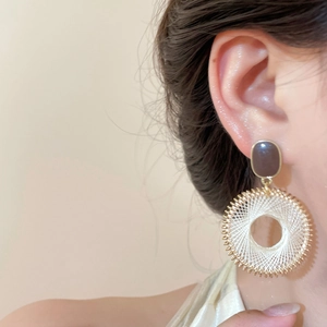 Gros plan de boucles d'oreilles rondes bohèmes avec maille dorée et tissage de fil blanc