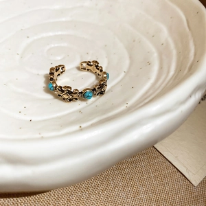 Macro view of vintage gold ring featuring blue resin stones and intricate filigree details