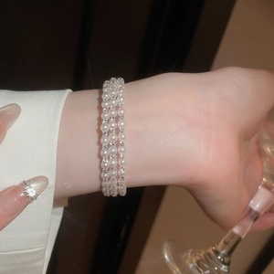 Macro detail of multi-layered pearl bracelet with sparkling diamond accents on wrist