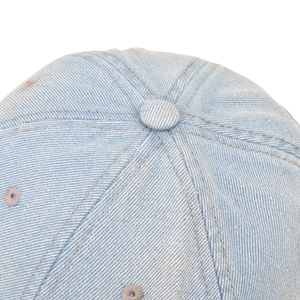 Detailed close-up of light blue washed denim baseball cap with embroidery and stitching