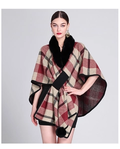 Detail of red and beige jacquard knit poncho with black faux fur collar and pom-poms