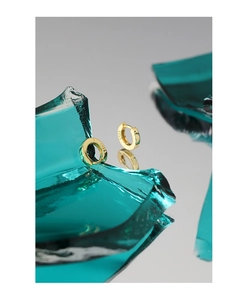 Macro shot of gold S925 sterling silver hoop earrings on artistic green glass