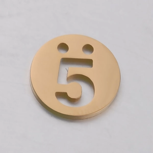 Détail d'un pendentif rond doré en acier inoxydable avec chiffre cinq ajouré et trous
