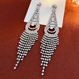 Macro detail of silver tassel earrings featuring sparkling crystal rhinestones set in metal