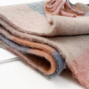 Close-up of thick checkered mohair scarf with pink blue grid patterns and long tassels