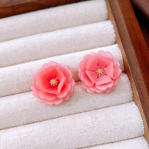 Detail shot of pink resin double-layer flower earrings with gold stamens in a jewelry box