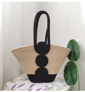 Detail of hand-woven cotton rope tote bag with black contrast handles and circular accents