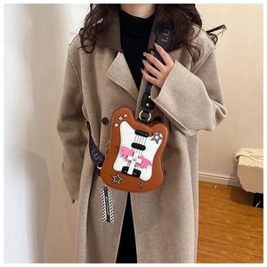 Detailed close-up of a guitar-shaped crossbody bag with star and wing accents on a model