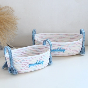 Detail of woven cotton storage baskets with Goodday embroidery and fringe tassels