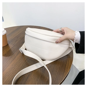 Detail view showing soft cream leather texture and adjustable strap of the crescent bag