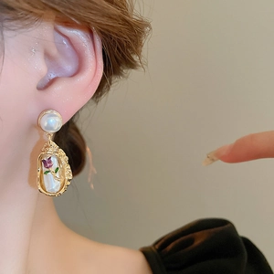 Macro shot of gold-plated tulip flower earrings with pearls and vintage shell inlay texture