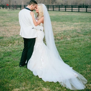 Detail view of a long ivory soft tulle wedding veil with an elegant lace mermaid gown