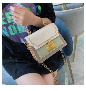 Detail view of stylish color-block handbag with gold T-lock and metal ring handle