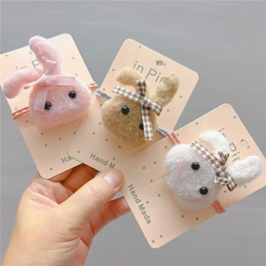 Three plush bunny hair accessories with ribbon bows in pink, brown, and white colors