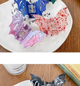 Detail of four colorful marble-textured bat hair claws for Halloween hairstyles