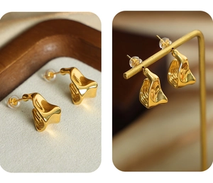 Detailed view of wave-shaped gold titanium earrings on textured surface and display