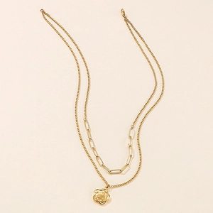 Detail of a double-layered gold necklace featuring a hollow flower pendant and paperclip chain