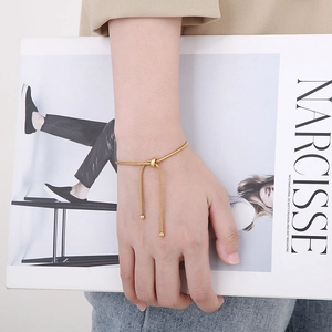 Detailed view of adjustable gold snake chain bracelet with central knot on model's wrist