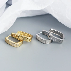 Macro shot of gold and silver U-shaped hoop earrings with micro-pave stones and floral cutouts