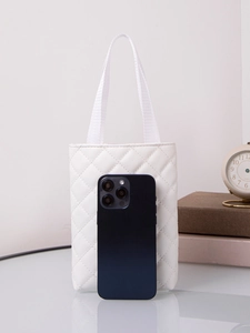 Mini white quilted handbag shown next to a smartphone for precise size scale comparison