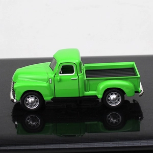 Side view of a vintage green alloy pickup truck model with reflection on a black surface