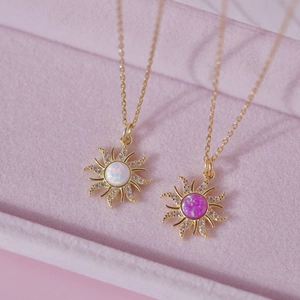 Detailed macro of gold necklaces with sunburst white and pink opal pendants in a jewelry box
