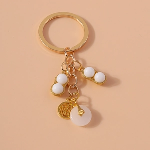 Golden keychain detail with resin jade peanuts and a Fu character lucky charm pendant