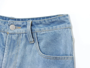 Vue macro détaillée de la taille en denim bleu clair avec bouton en métal et surpiqûres