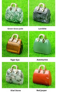 Mini handbag pendants carved from natural crystals with golden metal handles on green lawn