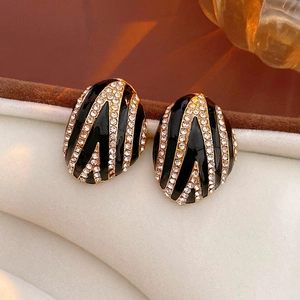 Vintage oval stud earrings with black enamel and gold accents set in a velvet jewelry box