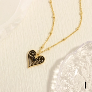 Macro shot of a black enamel heart pendant with golden outlines on a delicate beaded chain