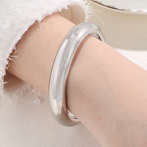 Close-up of a silver-colored thick polished metal bangle worn on a female wrist