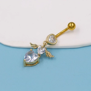 Macro detail of gold-plated belly ring with angel wings heart and white zircon