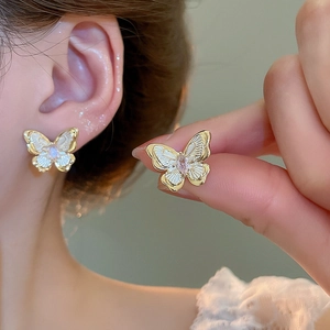 Detail of 18k gold plated butterfly stud earrings with pink gemstone and white wings