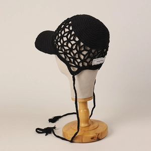 Detail of hand-crocheted black mesh baseball cap with stylish side label and tassels