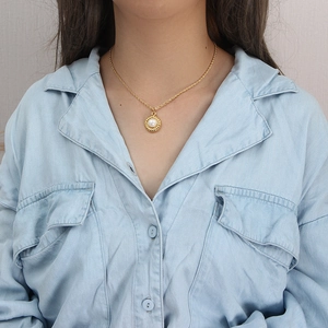 Détail d'un mannequin portant un collier tressé plaqué or 18 carats avec pendentif perle ronde