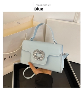 Primer plano del bolso azul claro con una gran hebilla de strass y asa de transporte