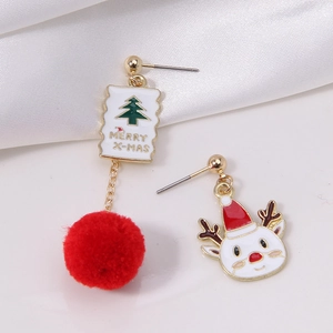 Macro view of Christmas earrings with fluffy pompoms and Merry X-MAS enamel details