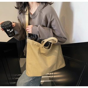 Detail of khaki canvas tote bag with reinforced metal rivets and wide shoulder strap