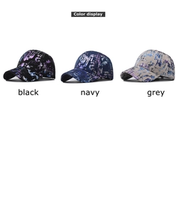 Detailed view of tie-dye baseball caps in black, navy, and grey with graffiti art