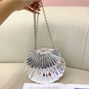 Detail of silver shell-shaped clutch with wave texture and metallic chain strap