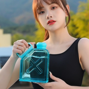 Close-up of teal square plastic fitness water bottle with handle and X-pattern design